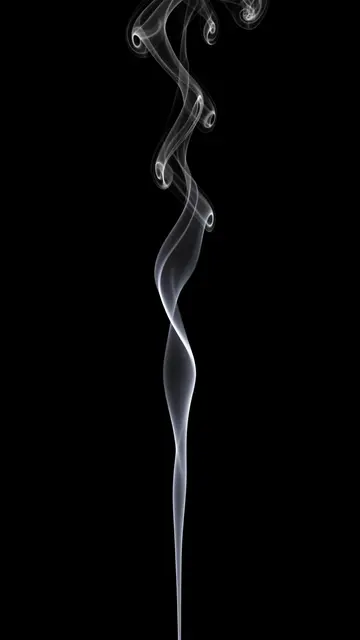 A thin vertical ribbon of white smoke rises in a lazy spiral against a solid pure black background