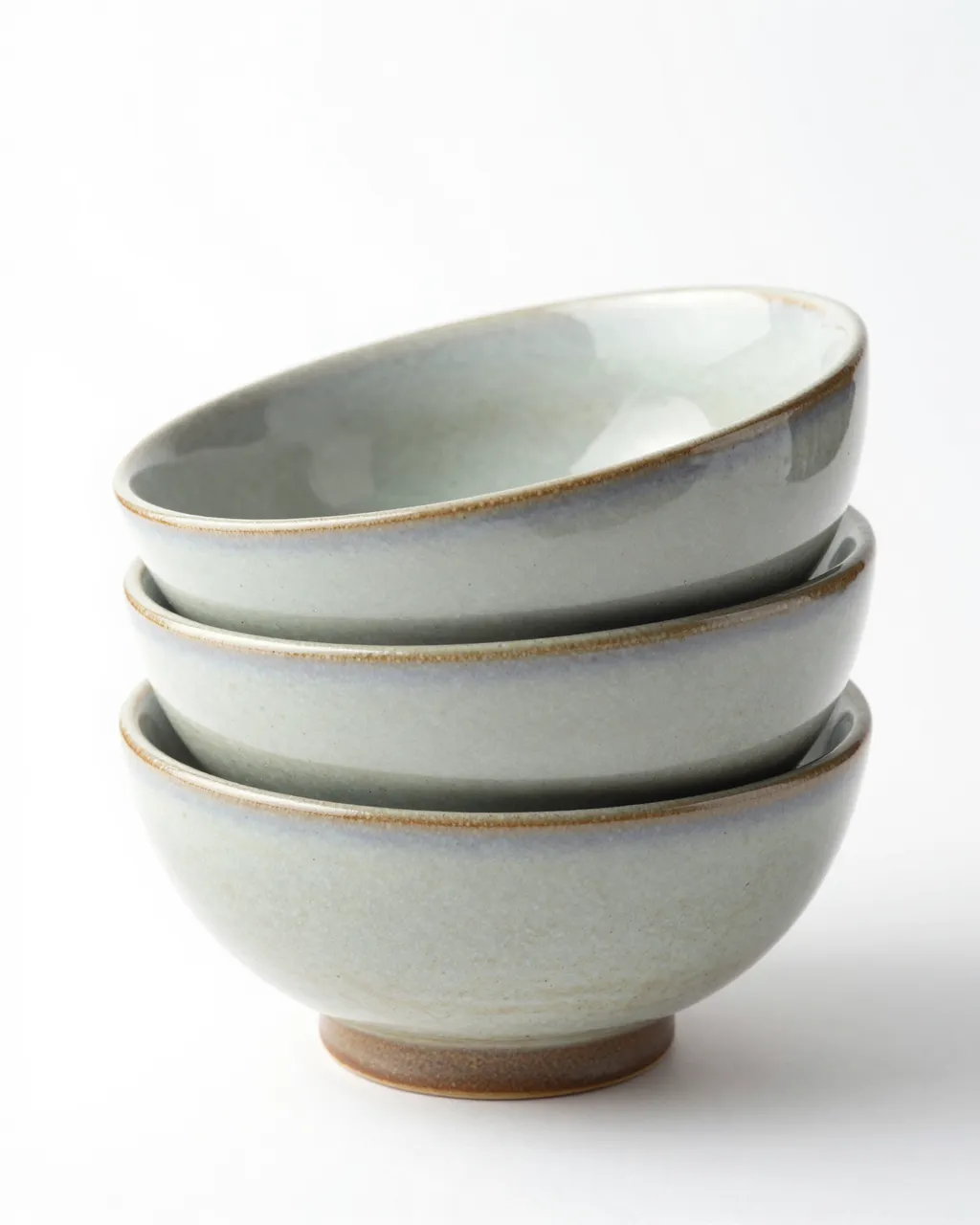 Three stacked speckled glazed ceramic bowls sit isolated on a plain white studio background.