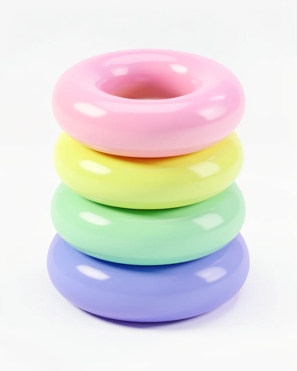 Four glossy stacked torus rings in soft pastel rainbow shades rest against a plain white background