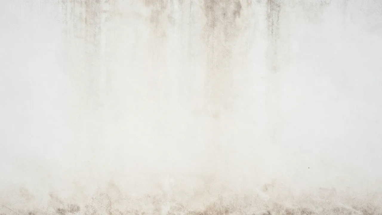 Full frame close up of a worn white plaster wall with faint vertical brown stains and rough grunge texture