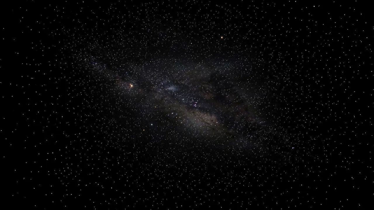 Dense star field with a faint sweeping milky galactic band against pure black space