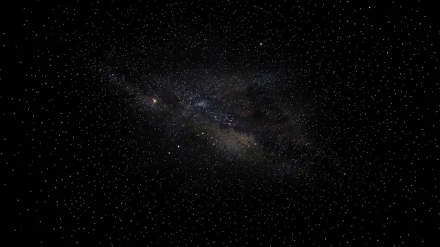 Dense star field with a faint sweeping milky galactic band against pure black space