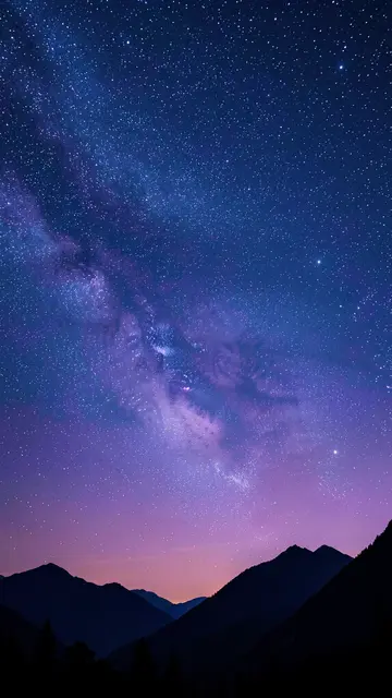 A vertical view of a dense starry night sky above dark silhouetted mountain peaks