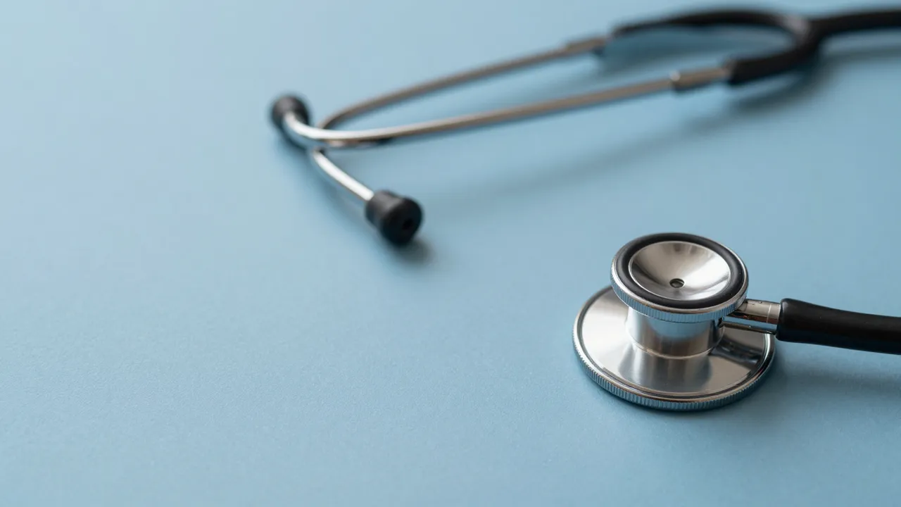 A stethoscope rests at the edge of a smooth pale blue surface with wide empty copy space.