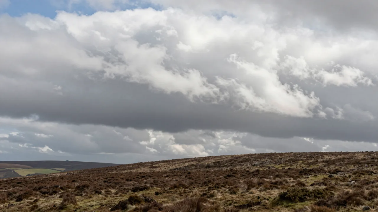 Turbulent wind-sculpted clouds drift across the sky above a wide open heather moorland ridge