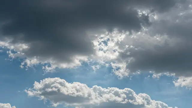 Dark storm clouds pull apart to reveal bright white fluffy clouds and clear patches of blue sky