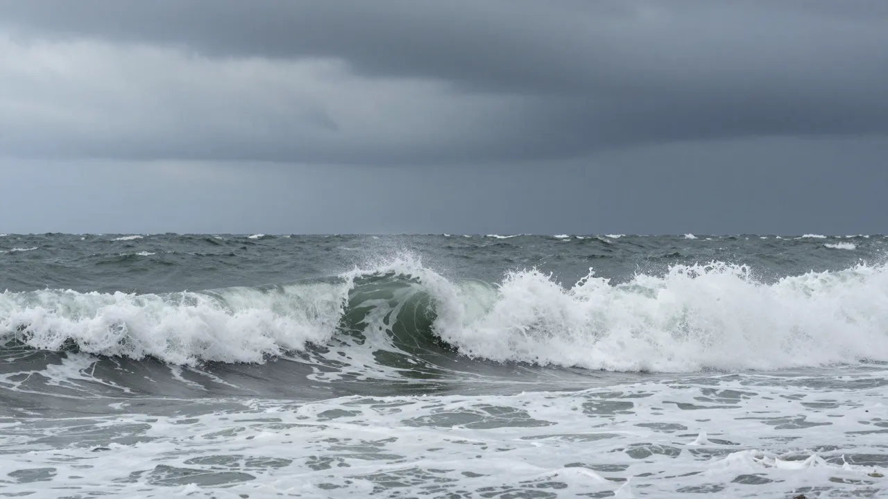 Turbulent crashing ocean waves roll beneath heavy dark overcast storm clouds