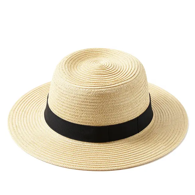 A wide-brimmed woven straw sun hat with a black ribbon band sits isolated on a plain white studio background