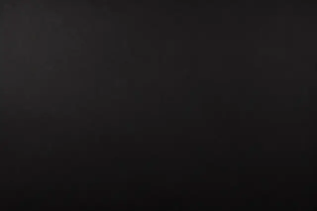 A full frame solid dark black surface with faint subtle grain texture