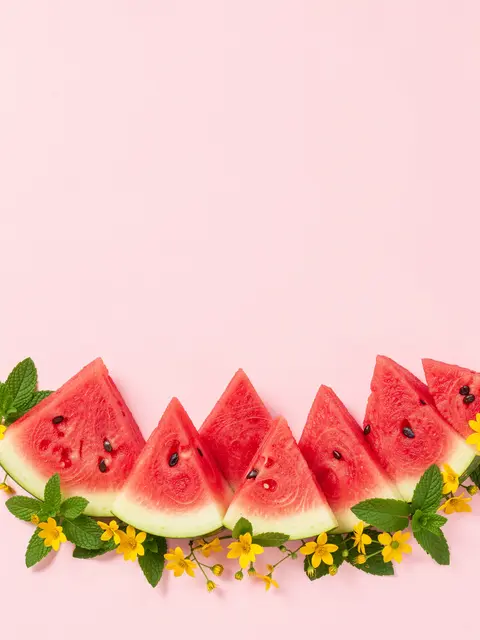 Horizontal bottom border of watermelon wedges, mint leaves and small yellow flowers on pale pink background