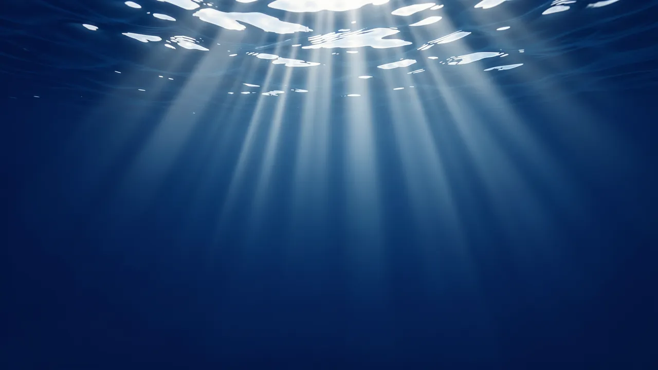 Sunlight rays stream down through deep blue open water from the rippled surface, with empty copy space below.
