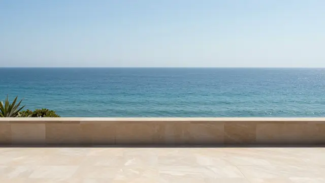 A stone terrace overlooking calm turquoise ocean under a clear bright blue sky