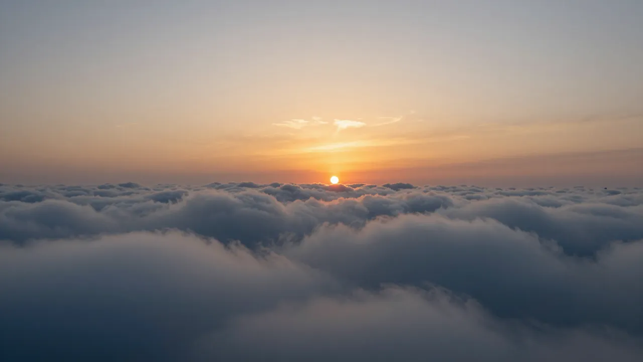 A high altitude view of a warm sunset sitting over a vast, rolling layer of clouds.