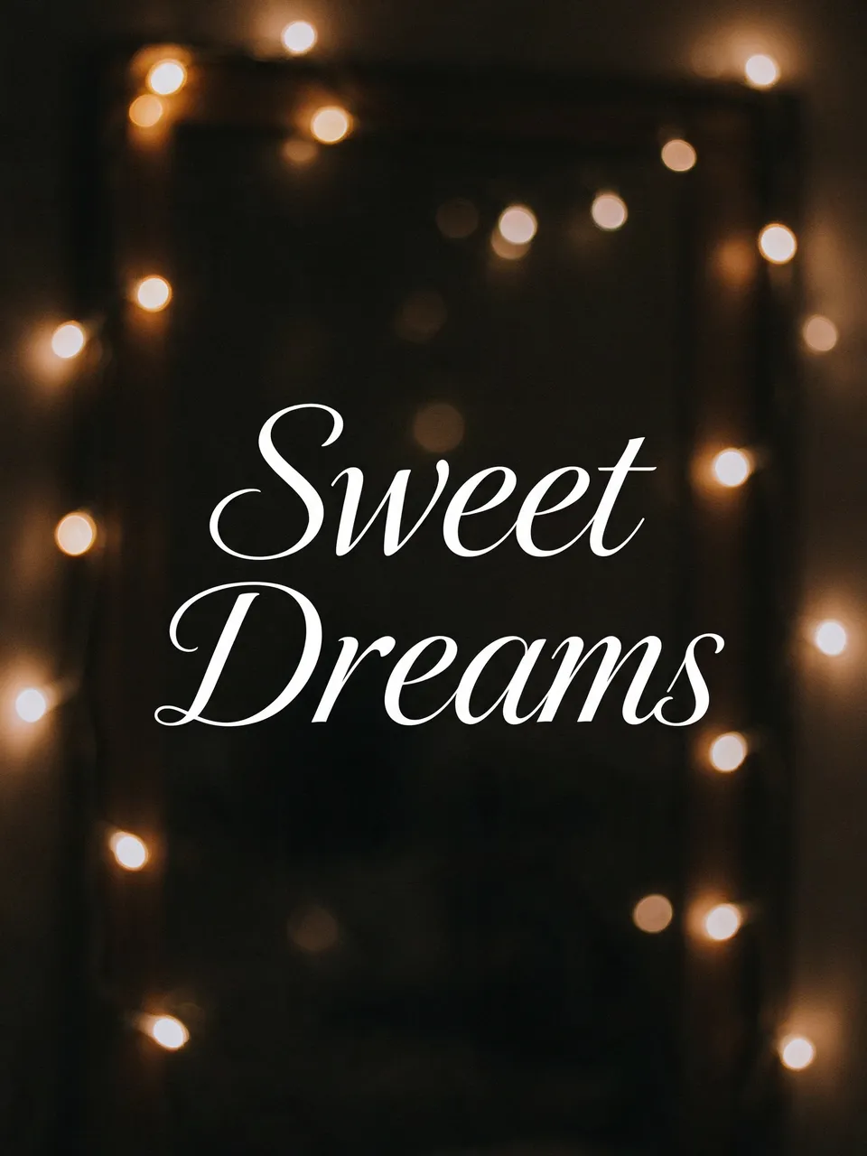 The text "Sweet Dreams" in white script centered over soft out-of-focus warm fairy light bokeh against a dark background