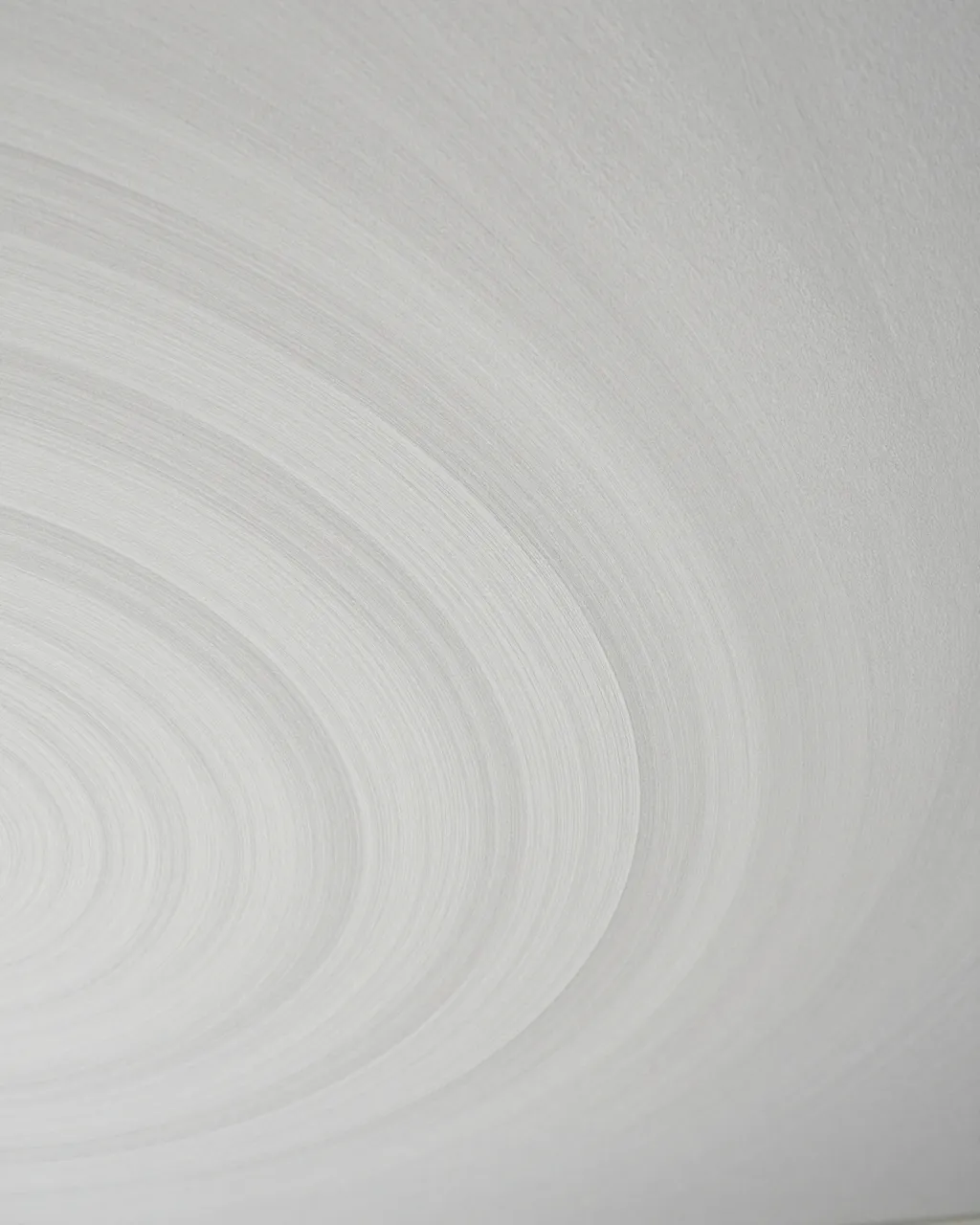 Full frame close-up of smooth white ceiling plaster with soft overlapping curved swirls