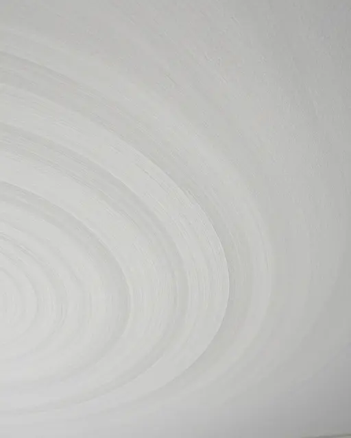 Full frame close-up of smooth white ceiling plaster with soft overlapping curved swirls
