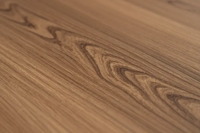 Close-up of polished olive wood surface with distinct swirling dark grain patterns