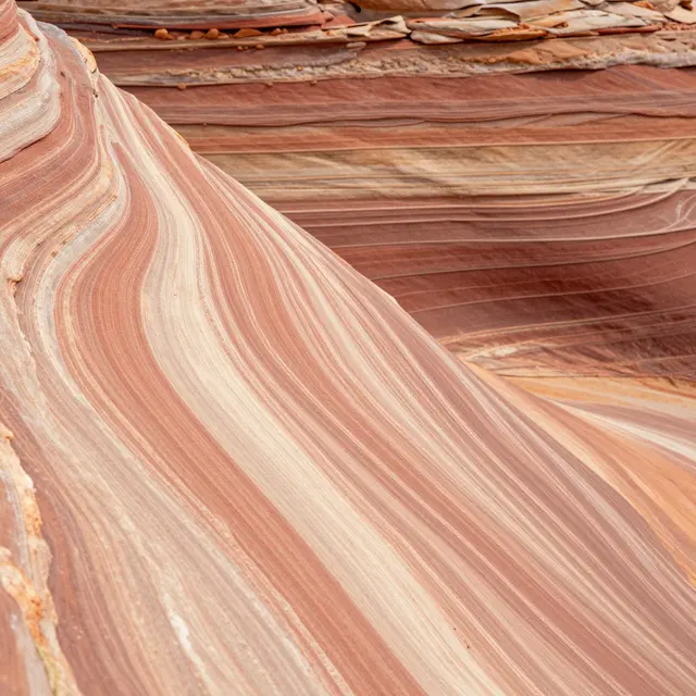 Close-up view of smooth swirling layered red and cream sandstone rock formations