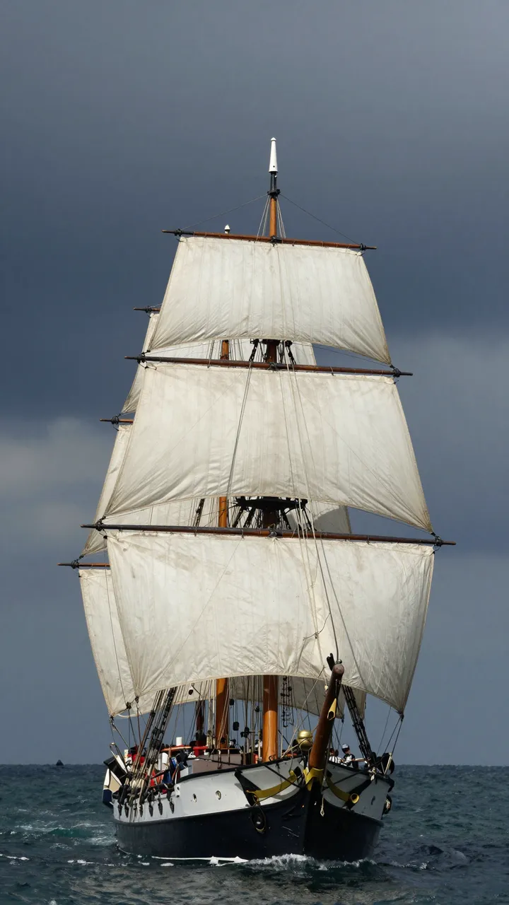 A tall sailing ship with full billowed sails moves across dark choppy sea under a heavy stormy overcast sky.