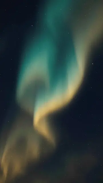 Rippling teal and gold aurora light glows over a starry dark navy night sky