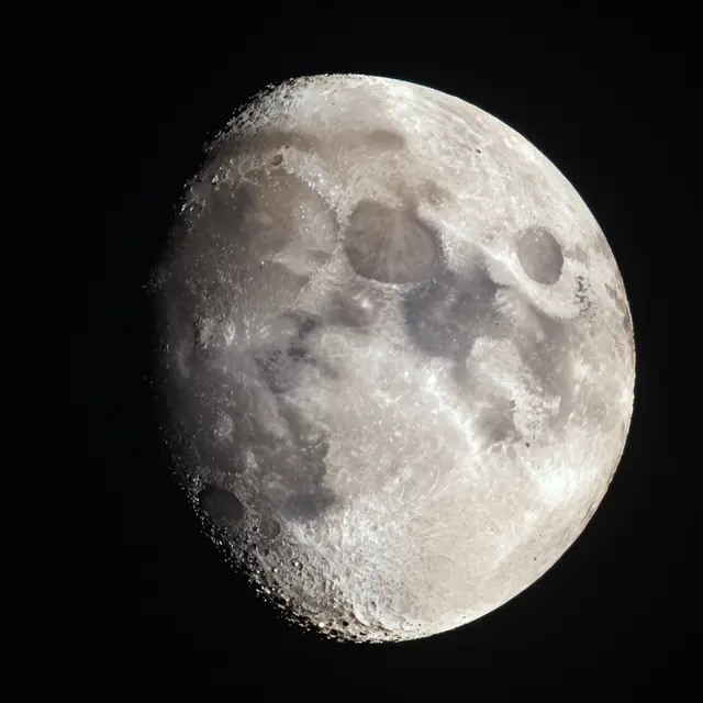 Close-up telescope view of a cratered gibbous moon set against deep black space
