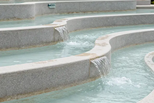 Curved terraced stone pools have clear turquoise water spilling gently over their tiered edges