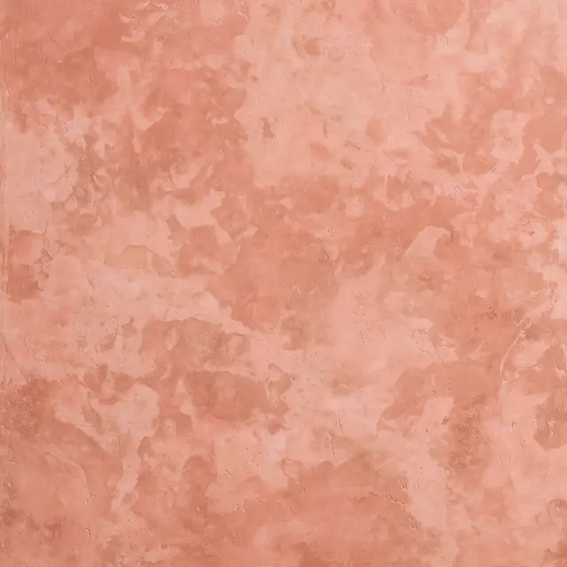 Full frame straight-on view of sun-faded terracotta pink limewash plaster with soft tonal blotches