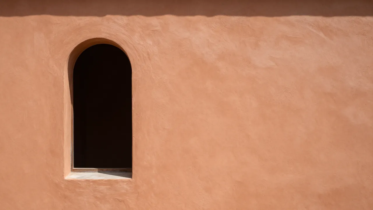 Textured warm terracotta plaster wall featuring a narrow dark arched window on the left side