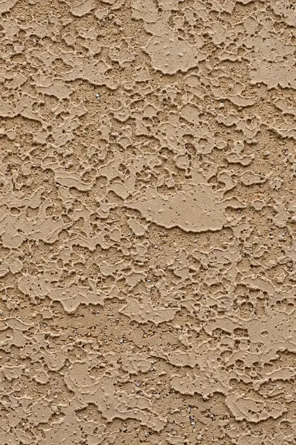 Full frame close-up of rough patterned tan stucco wall texture under flat even lighting