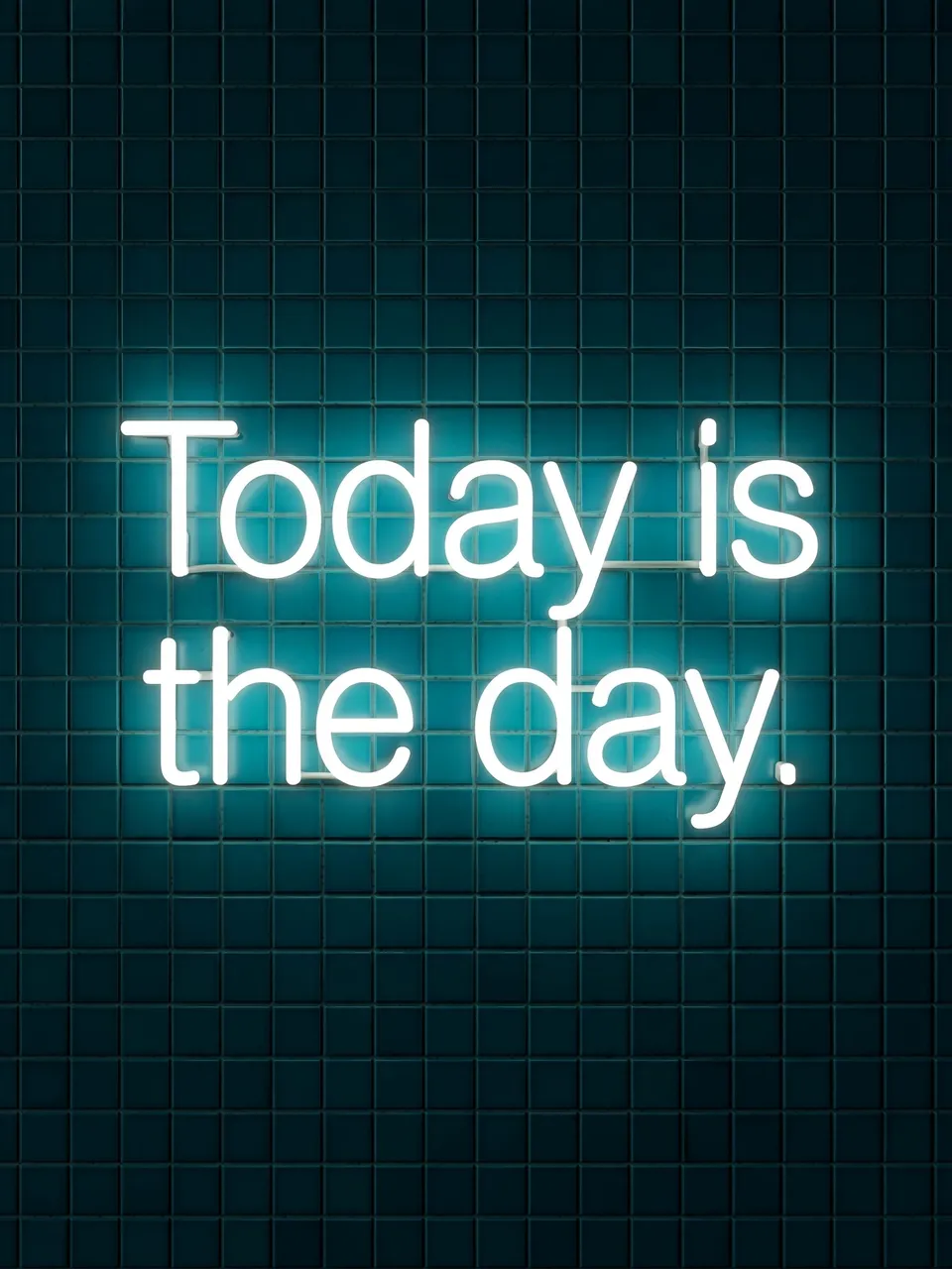 Glowing white neon sign reading "Today is the day." mounted on a dark teal tiled wall
