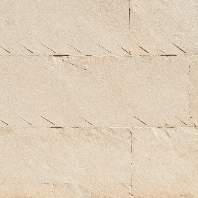 Full frame close-up of buff tooled sandstone blocks with diagonal chisel marks under even lighting