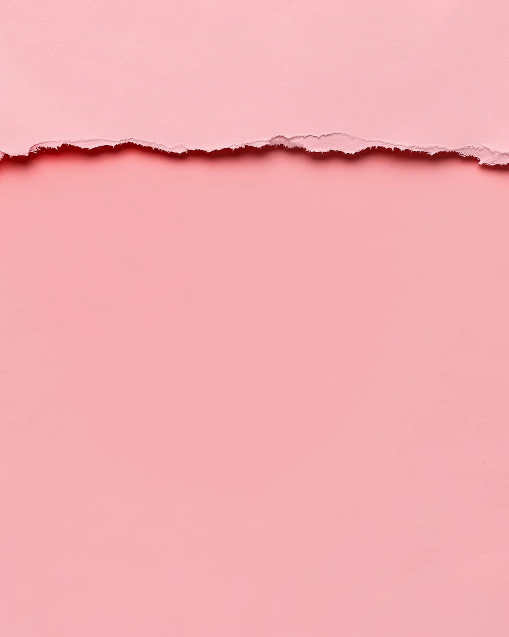 Soft pink paper with a ragged torn horizontal edge revealing a darker red shadow below the top layer.