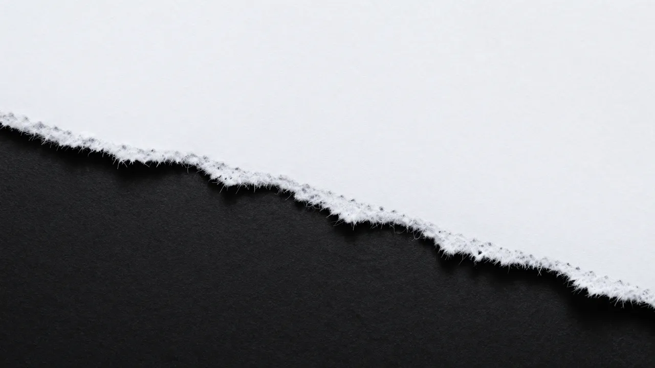 A close-up of a rough, frayed torn white paper edge resting above a solid black background