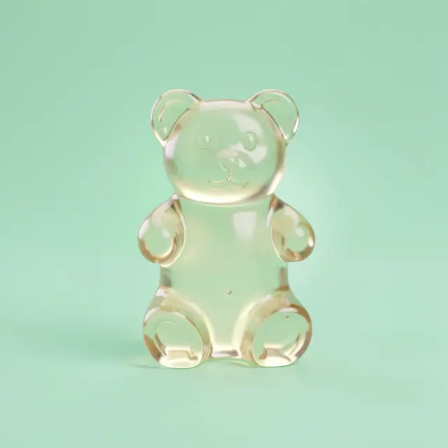 A pale translucent gummy bear stands centered against a soft mint green background with a gentle glow.