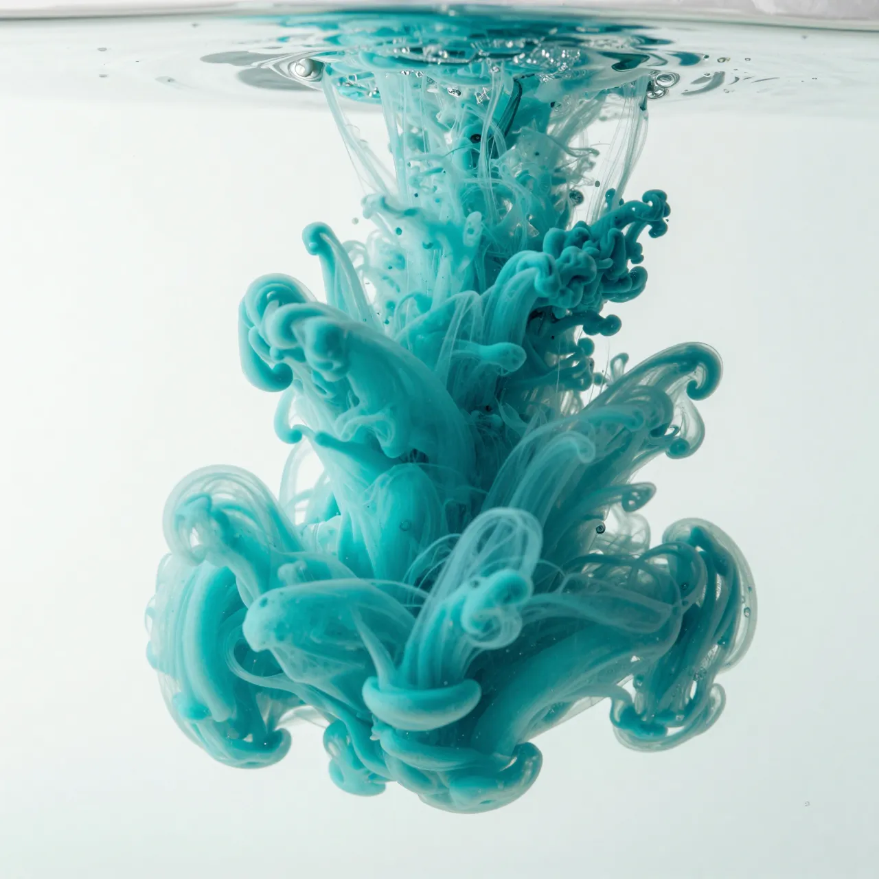 Swirling turquoise ink ribbons unfurl through clear water against a pale white background