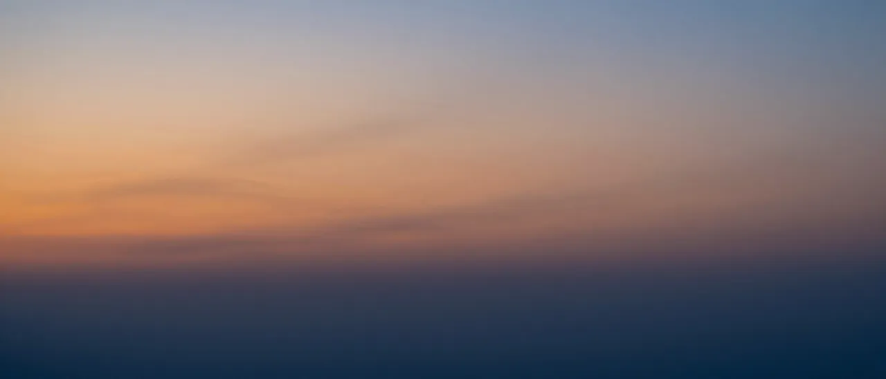 Smooth twilight sky gradient transitioning from warm orange near the horizon to deep cool blue