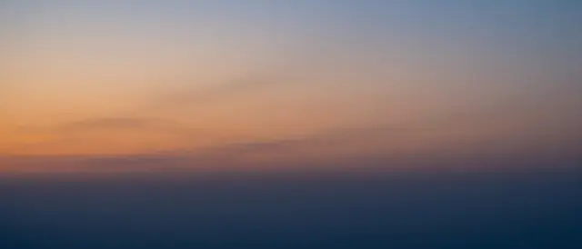 Smooth twilight sky gradient transitioning from warm orange near the horizon to deep cool blue