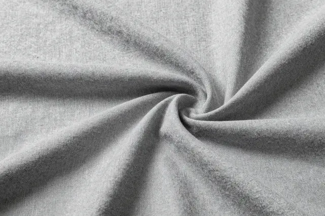 Close-up of softly wrinkled washed gray linen fabric twisted into a spiral center.