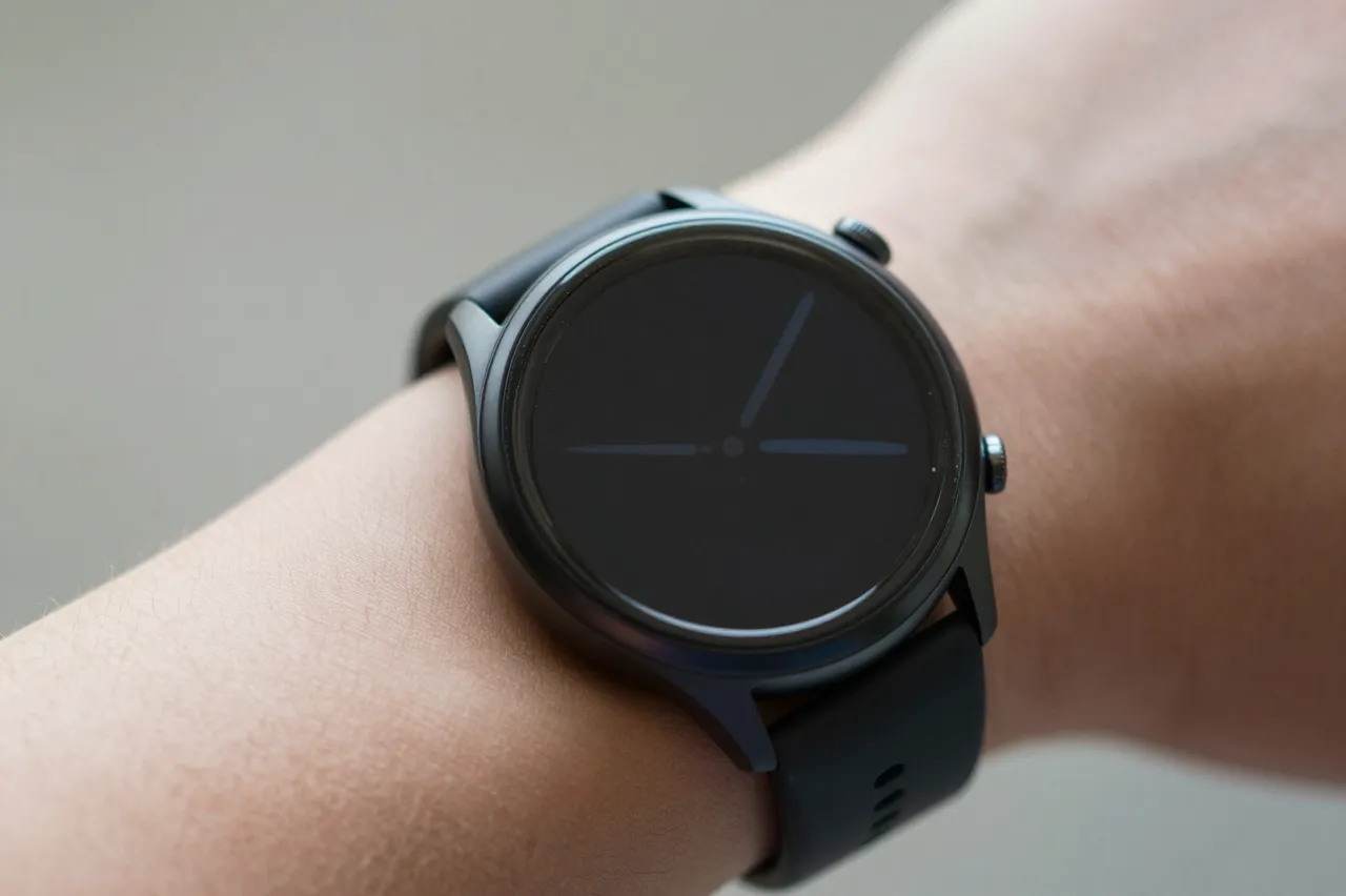 Close-up of an unbranded round smartwatch with a dark screen worn on a person's wrist