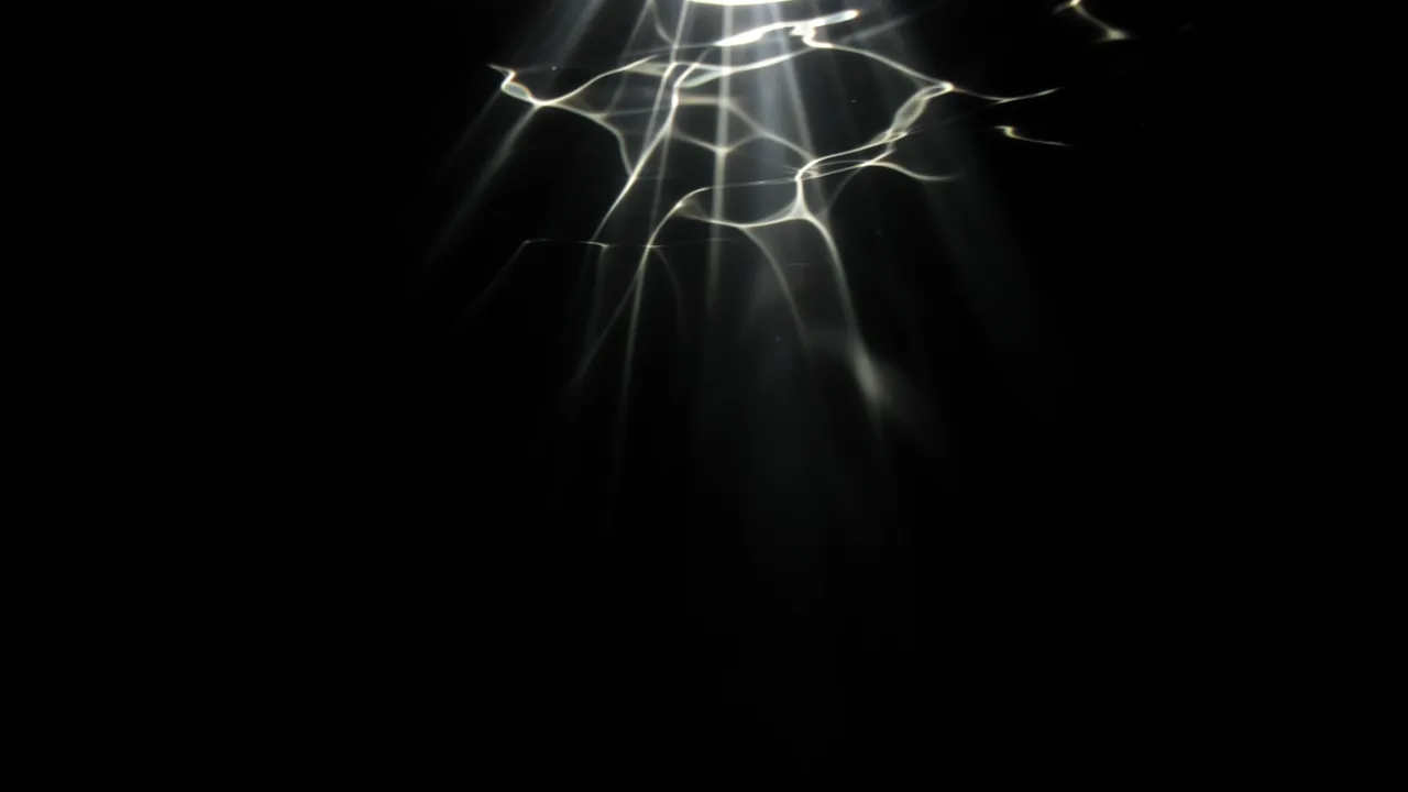 Shimmering wavy light rays stream downward against a solid pure black background