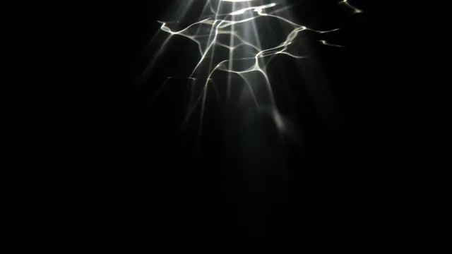 Shimmering wavy light rays stream downward against a solid pure black background