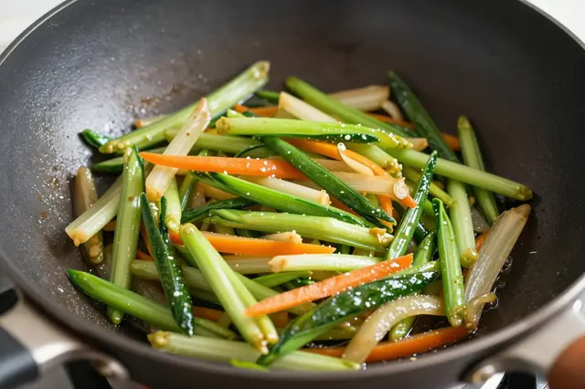 Sliced mixed vegetables sizzle in oil inside a dark non-stick wok.