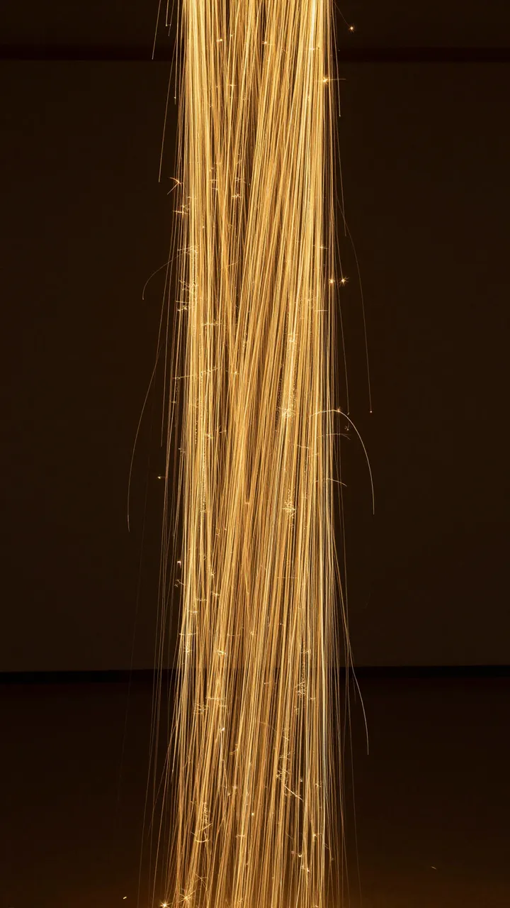 Swirling vertical column of glowing golden light lines against a dark empty background