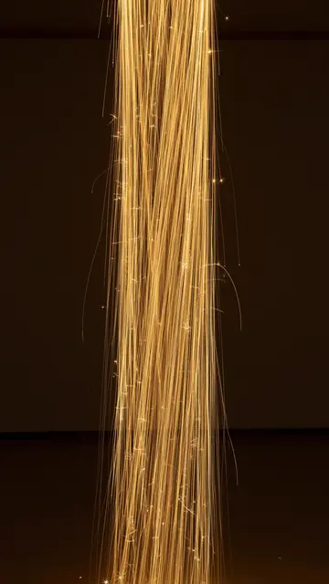 Swirling vertical column of glowing golden light lines against a dark empty background