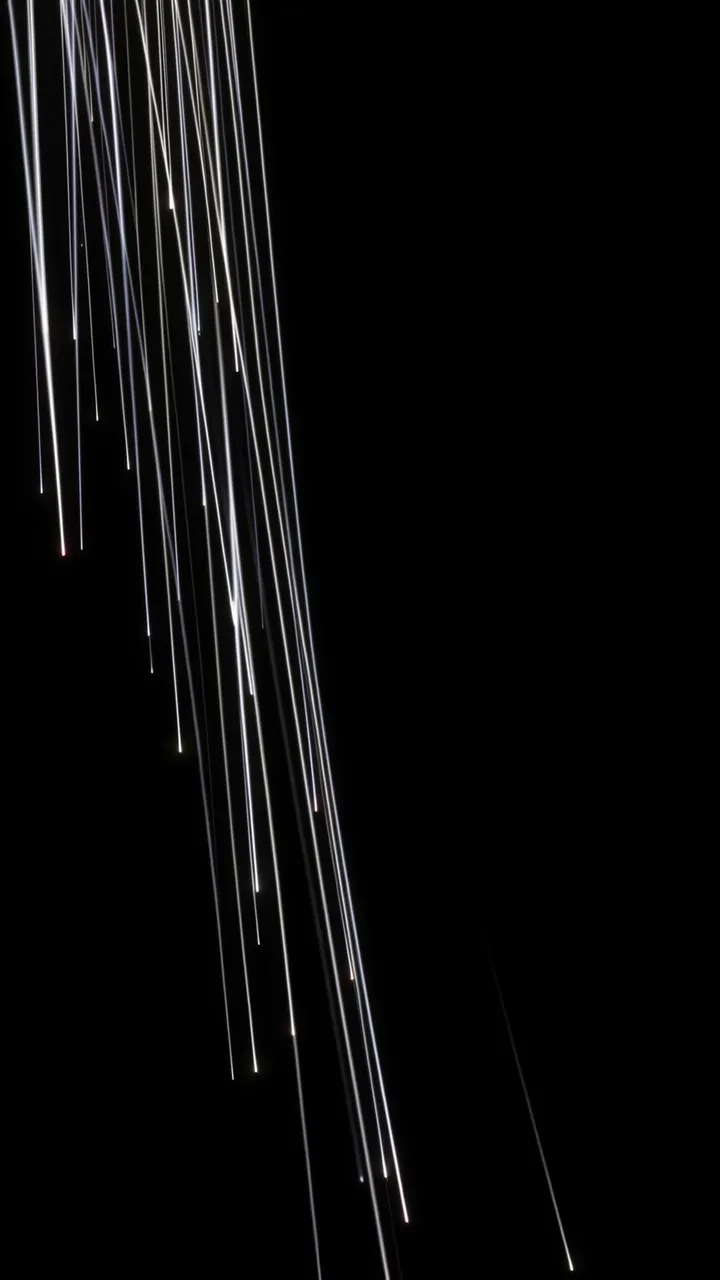 Thin bright white streaks fall diagonally from the upper left against a solid pure black background