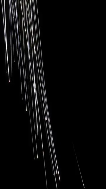 Thin bright white streaks fall diagonally from the upper left against a solid pure black background