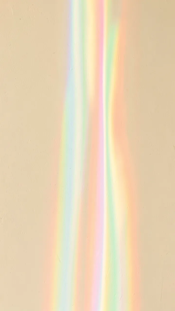 Soft vertical rainbow prismatic light bands stream down a textured cream wall