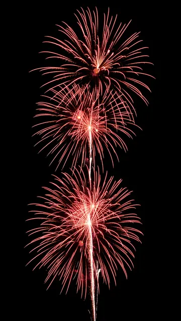 Stacked red and white firework bursts glow brightly against a solid pure black background