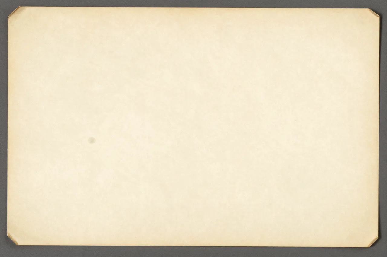 A full frame of yellowed vintage paper with folded corner edges resting on a dark gray background
