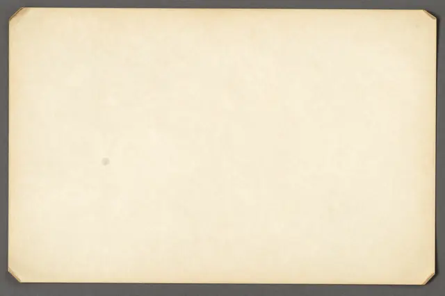 A full frame of yellowed vintage paper with folded corner edges resting on a dark gray background
